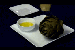 person dipping an artichoke in melted butter